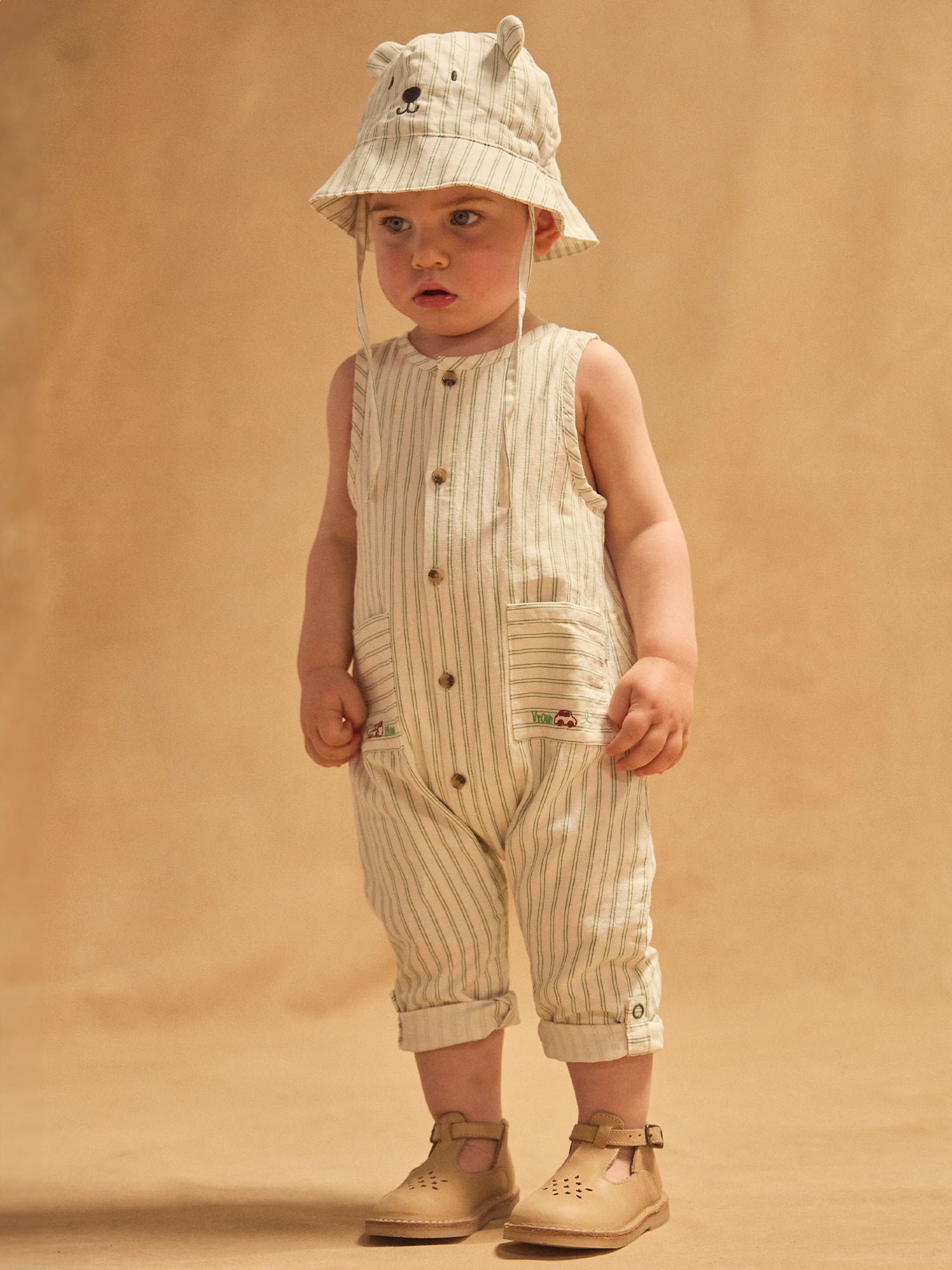 Salopette bianca a righe verdi per bebè ragazzo.